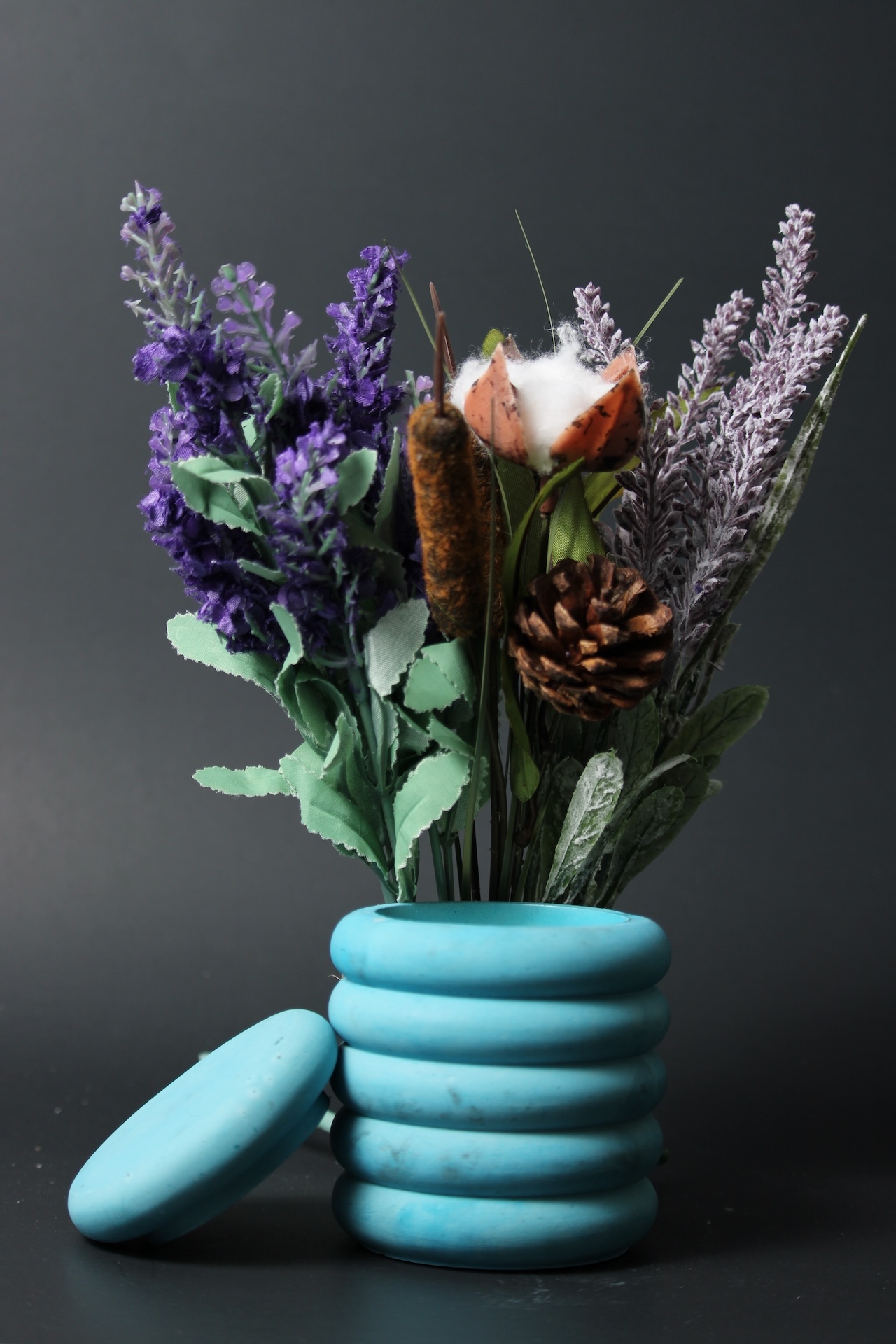 Flower arrangement in teal ceramic vase, dark background