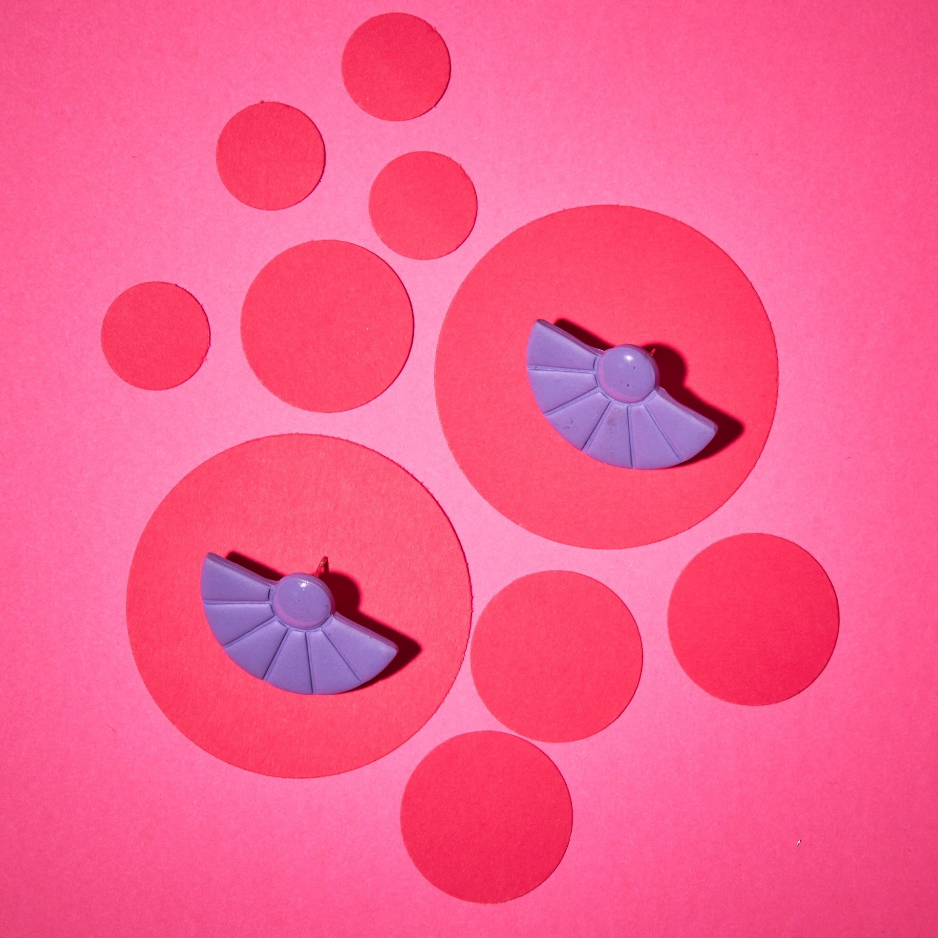 Purple fan earrings on pink circles composition
