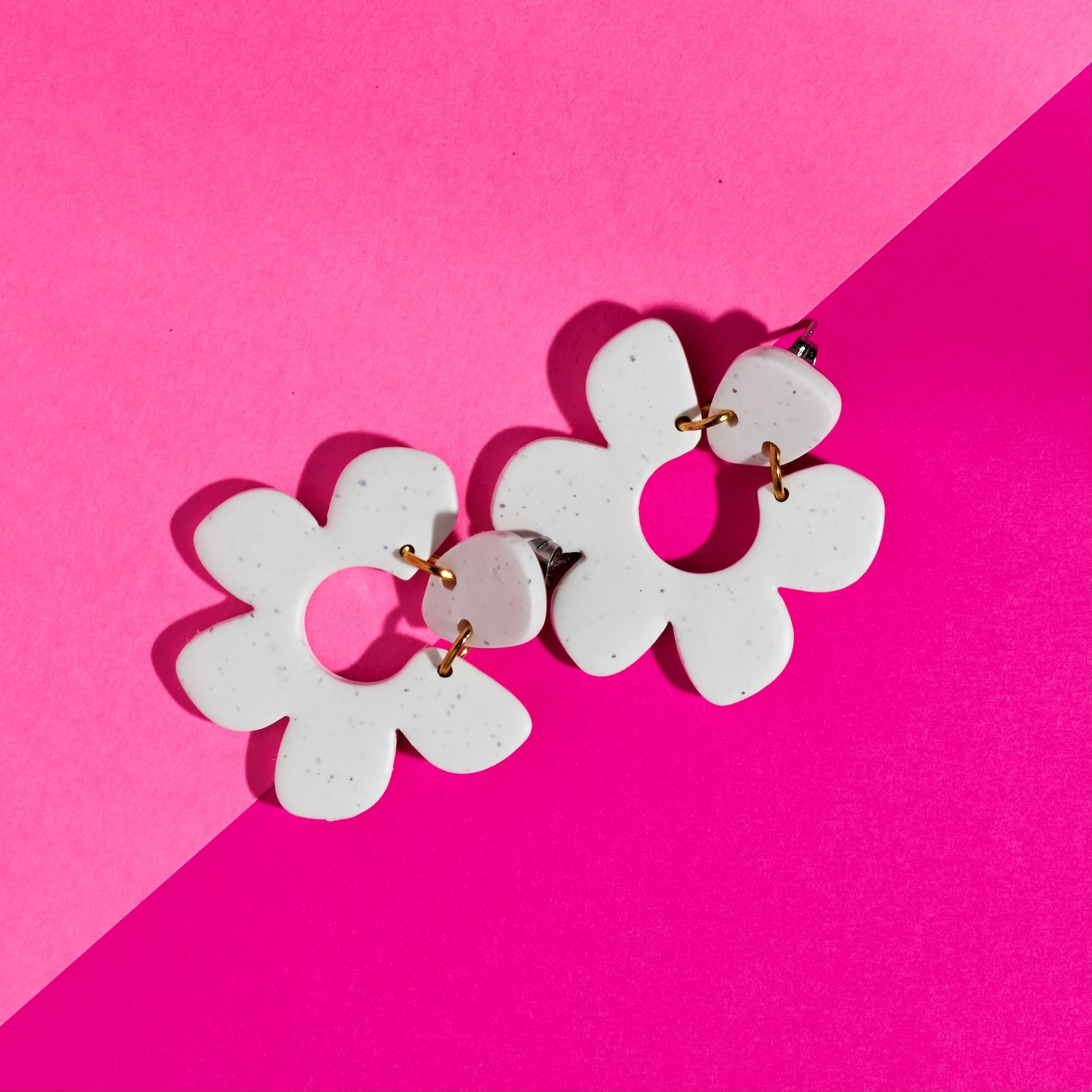 White flower earrings on split pink background